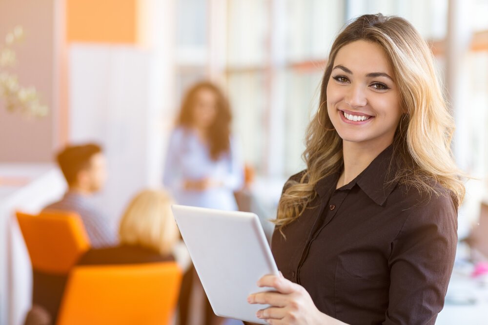 portrait of young business woman at modern startup office interior, team in meeting in background