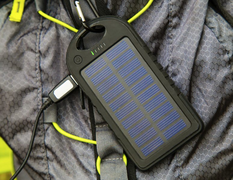 Portable solar cell hanging on tourist backpack closeup